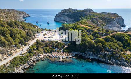 Sulla spiaggia Plaka in primo piano nella baia di Ladiko, sullo sfondo la popolare baia di Anthony Quinn sull'isola greca di Rodi. Foto Stock