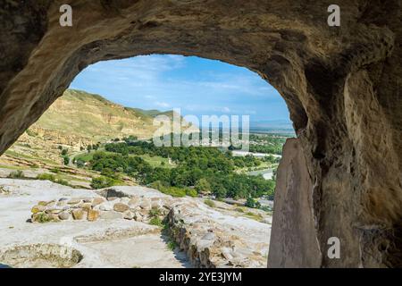 Vista incorniciata della valle dall'interno della città grotta di Uplistsikhe. Antica città pre-cristiana scavata nella roccia e monastero in Georgia. Patrimonio dell'umanità dell'UNESCO. Foto Stock