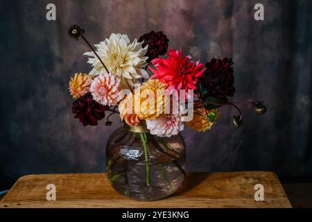 Grande bouquet di fiori autunnali dahlias e asters in tonalità arancio, Bordeaux, bianco e giallo in un vaso in piedi su una panchina di legno Foto Stock