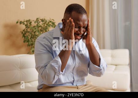 ragazzo afroamericano che tiene la testa e soffre di mal di testa e emicrania a casa, stress a casa Foto Stock