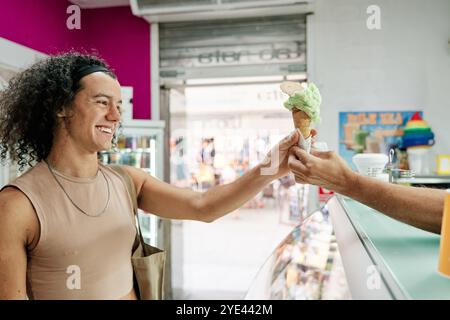 uomo che compra un cono di gelato al pistacchio in un negozio Foto Stock