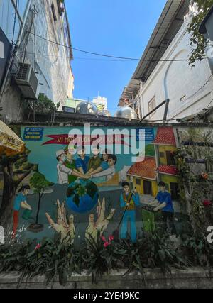 Hanoi, Vietnam: Vita quotidiana, skyline e murales nelle strade affollate del centro della capitale, con auto e moto che passano a tutta velocità Foto Stock