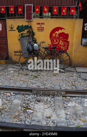 Vietnam: Bandiere e biciclette vietnamite, Hanoi Train Street, stretta circonvallazione ferroviaria che vede i treni passare tutti i giorni vicino agli edifici su entrambi i lati dei binari Foto Stock