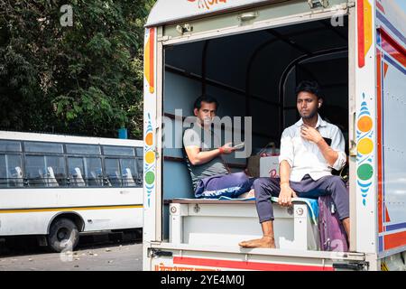 Uomini indiani che viaggiano su un camion a Mumbai, India. I lavoratori viaggiano dietro un furgone. Gli uomini indiani viaggiano dietro a un camion aperto. Foto di viaggio, edi Foto Stock