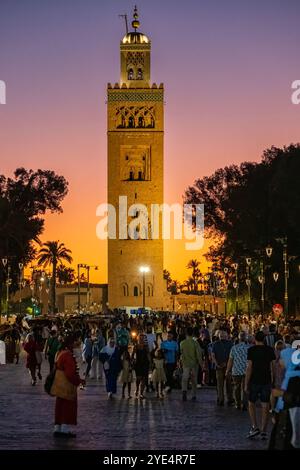 Marrakech, Marocco. Una vista della moschea Kutubiyya situata nella medina di Marrakech. La vista e' nelle prime ore della sera da un affollato Jemaa el-Fnaa Foto Stock