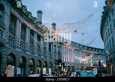 Regent Street a Londra con le famose decorazioni natalizie degli angeli, le luci festive e l'atmosfera e l'atmosfera natalizia, l'ora blu, i semafori Foto Stock