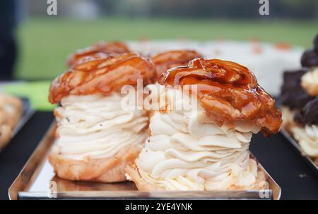 Dessert locale chiamato Pinwheel o corona con un'enorme pila di panna e cappello saporiti con glassa lucente al caramello, vista frontale bassa, primo piano Foto Stock