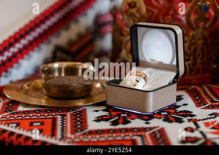 Squisito anello in oro in elegante scatola su sfondo tessile tradizionale. Foto Stock