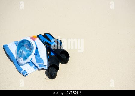 Pinne, un asciugamano e una maschera subacquea sulla sabbia sulla riva dell'Oceano Indiano. Isole Maldive. Foto Stock