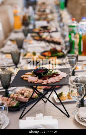 La mostra Abundant Feast presenta una varietà di antipasti e bevande su un lungo tavolo da pranzo. Foto Stock