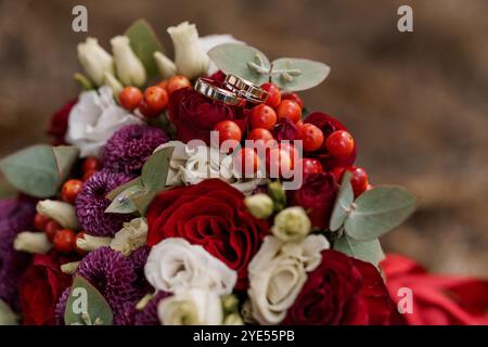 Elegante bouquet floreale con anelli da sposa circondati da vivaci fiori. Foto Stock