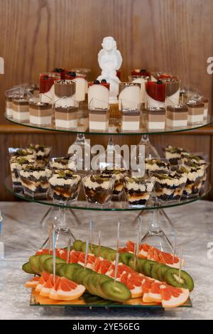 Elegante espositore di dessert con dolci assortiti e decorazioni di frutta. Foto Stock