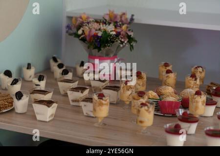 Deliziosa mostra di dessert con budini, torte e fiori. Foto Stock