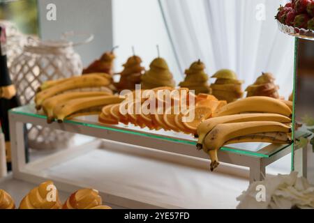 Vibrant Fruit display con banane, arance ed eleganti coni di pera. Foto Stock