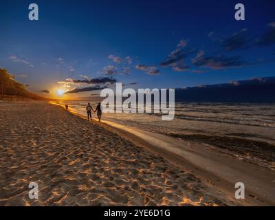 Una coppia che si tiene per mano al tramonto sulla spiaggia del Mar Baltico, Germania, Meclemburgo-Pomerania occidentale Foto Stock