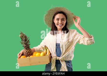 Agricoltore femmina con scatola di frutta su fondo verde Foto Stock