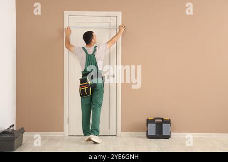 Un lavoratore maschio che misura la porta a casa Foto Stock