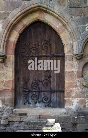 Antica porta in legno e metallo in un muro di pietra Foto Stock