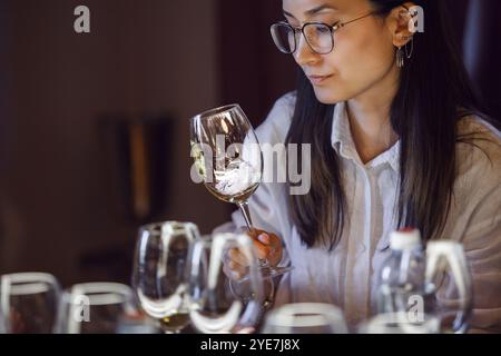 Donna che tiene un bicchiere di vino al tavolo Foto Stock