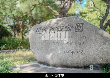 Marciapiede con una fila di alberi e una fila di panchine. Una fermata dell'autobus si trova nel mezzo del marciapiede Foto Stock