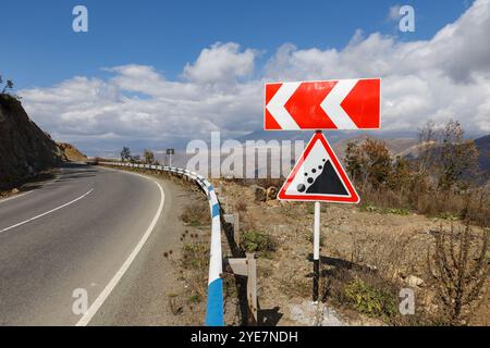 Cartelli stradali in caduta di pietre e direzione di rotazione sulla strada sulle montagne dell'Armenia Foto Stock