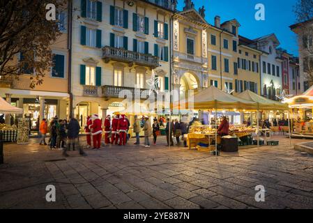 Mercatino di Natale e luci di natale al tramonto, folla di persone che fanno shopping tra le bancarelle. Centro storico di Varese, corso Matteotti Foto Stock