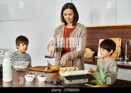 Una gioiosa nonna asiatica condivide con i suoi due adorabili nipoti la gioia di cucinare le prelibatezze natalizie. Foto Stock