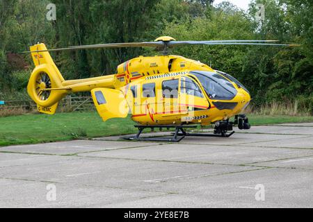 L'ambulanza gialla East Anglian Air dopo aver risposto a un'emergenza nel Suffolk rurale di Framlingham attende con l'equipaggio in un parcheggio Foto Stock