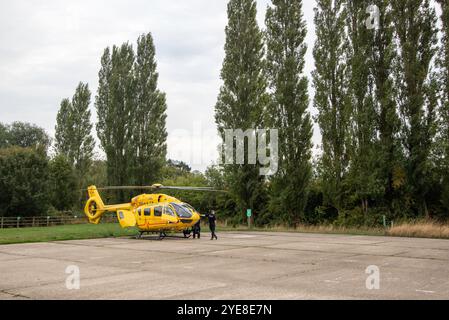 L'ambulanza gialla East Anglian Air dopo aver risposto a un'emergenza nel Suffolk rurale di Framlingham attende con l'equipaggio in un parcheggio Foto Stock