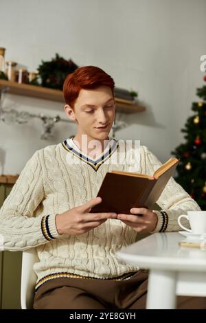Il giovane siede comodamente, perso in un libro, circondato da decorazioni festose. Foto Stock