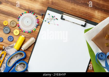 Colorate forniture di cucito disposte intorno a un portadocumenti vuoto su un tavolo di legno Foto Stock