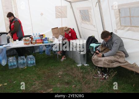 KIEV, UCRAINA – 30 OTTOBRE 2024 – Un residente di un condominio colpito dal relitto di un drone russo abbattuto siede con il suo gatto in una tenda mobile allestita per fornire aiuto alle vittime, Kiev, capitale dell'Ucraina Foto Stock