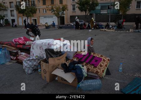 Beirut, Libano. 27 ottobre 2024. Si vede una donna seduta accanto ai suoi effetti personali per la strada di Beirut. Mentre la guerra tra Israele e Hezbollah continua in Libano, più di 1, 2 milioni di persone sono state colpite e sfollate dalle loro case, una cifra secondo le autorità libanesi. I rifugi in diverse città sono saturi e molti che non hanno mezzi finanziari hanno optato per vivere per strada. (Immagine di credito: © Ashley Chan/SOPA Images via ZUMA Press Wire) SOLO PER USO EDITORIALE! Non per USO commerciale! Foto Stock
