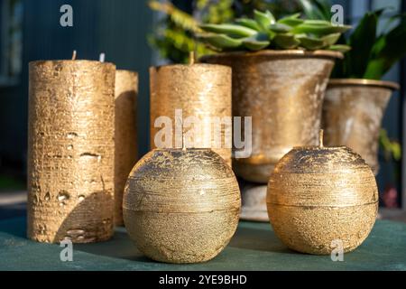 Accanto alle fioriere decorative si trovano lussuose candele dorate di varie forme, che mettono in risalto un elegante ambiente esterno immerso nella calda luce del sole. Foto Stock