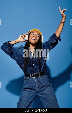 Una giovane donna ama ballare mentre indossa il suo outfit autunnale alla moda, irradiando gioia. Foto Stock