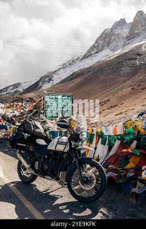 Fotu la, un passo di montagna lungo l'autostrada Srinagar-Leh nella catena montuosa Zanskar dell'Himalaya in India, con bandiere di preghiera buddiste e una motocicletta... Foto Stock