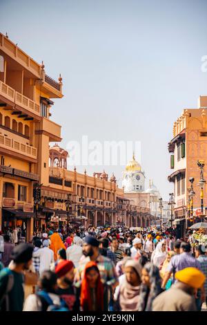 Strada trafficata piena di pedoni e vista del Tempio d'Oro in lontananza nella città di Amritsar, India; Amritsar, Punjab, India Foto Stock