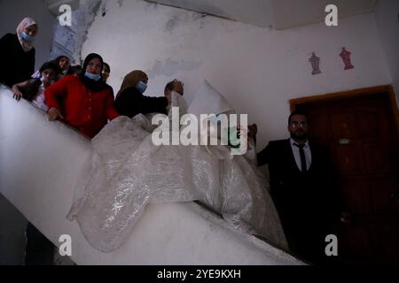 Gaza, Palestina. 9 settembre 2020. Una coppia palestinese si sposa a Gaza City in una piccola cerimonia nuziale limitata ai membri della famiglia più stretti, con distanziamento sociale e maschere facciali parte dell'evento. Dal 24 agosto, quando i casi di Covid-19 sono stati individuati per la prima volta tra la popolazione della Striscia di Gaza, si è registrato un drastico aumento delle infezioni da virus nel territorio palestinese. Le autorità hanno lottato con l'aumento del numero di casi a Gaza, una delle aree più densamente popolate del mondo e con un'infrastruttura sanitaria sovraccarica e scarsamente alimentata Foto Stock