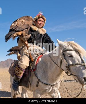 Cacciatore di aquile mongole a cavallo con aquila d'oro (Aquila chrysaetos) al Festival dell'aquila in Mongolia; Olgii, Mongolia Foto Stock