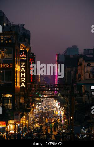 Scena di strada di notte nella Vecchia Delhi, con grandi cartelli illuminati e affollata di pedoni; Old Delhi, Delhi, India Foto Stock