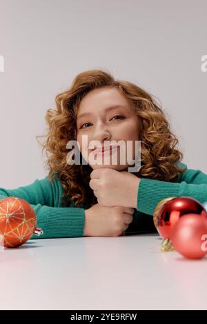 Una giovane donna allegra prepara regali circondati da ornamenti natalizi, abbracciando lo spirito festivo. Foto Stock