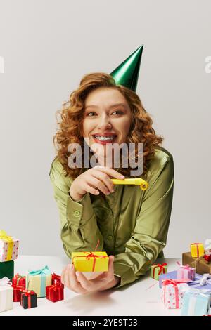 Una giovane donna con i capelli ricci si posa felicemente mentre indossa un cappello da festa. Foto Stock