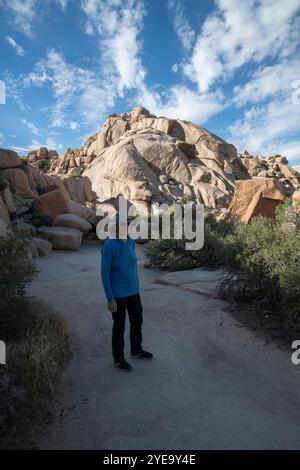 Ritratto di una donna che sorride e posa per la macchina fotografica accanto alle iconiche rocce di granito del Joshua Tree National Park Foto Stock