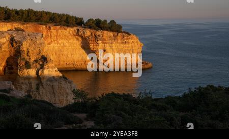 Spiaggia di Benagil al tramonto, con aspre scogliere lungo la costa dell'Algarve in Portogallo; Benagil, Lagoa, Faro, Portogallo Foto Stock