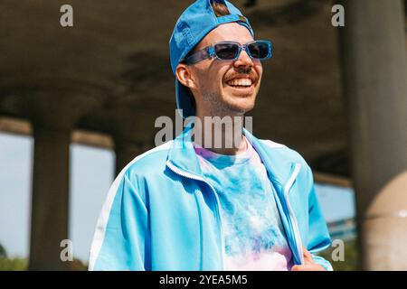 Giovane felice con abiti casual che indossano cappello e occhiali da sole Foto Stock
