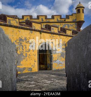 Facciata intemprata dell'architettura gialla del forte di Sao Tiago nella città costiera di Funchal sull'isola di Madeira, Portogallo Foto Stock