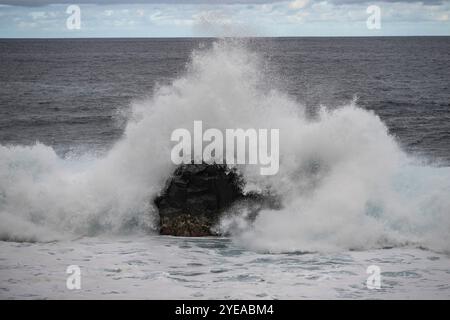 Fai surf schiantandoti su una formazione rocciosa presso il punto di riferimento naturale Ilheus da Ribeira da Janela lungo la costa dell'isola di Madeira, Portogallo Foto Stock