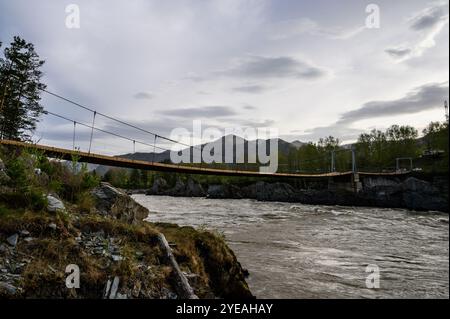 Elekmonar, Repubblica di Altai, ponte sospeso sul veloce fiume montuoso Katun nel villaggio di Elekmonar, distretto di Chemalsky. Isole rocciose affilate nel m Foto Stock