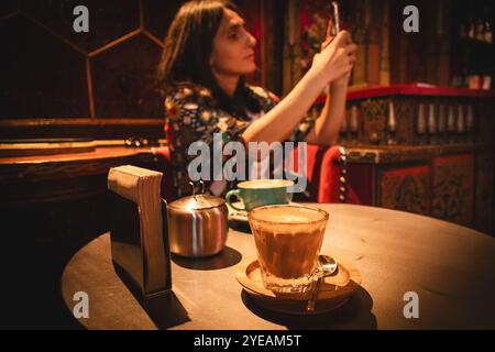 Yerevan, Armenia - 19 ottobre 2024: Donna turistica gusta bere caffè fresco cappuccino scatta una foto per blogging Lumen Coffee 1936 Cafe. Famou speciale Foto Stock