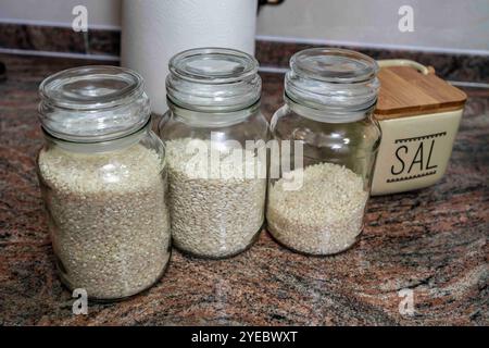 Vasi di vetro riempiti di riso e un agitatore di sale sul lato Foto Stock